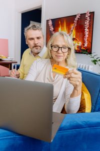 Image of a couple with a credit card entering the details into a laptop